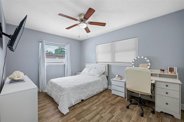 bedroom featuring ceiling fan, light hardwood / wood-style flooring, and a textured ceiling