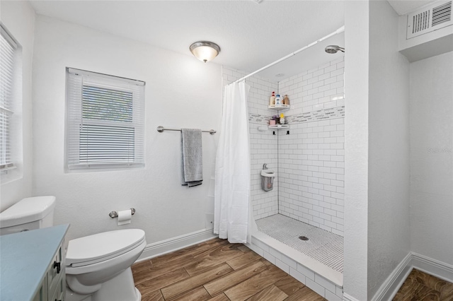 bathroom featuring wood-type flooring, toilet, curtained shower, and vanity