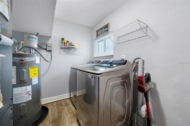 washroom featuring a textured ceiling, wood-type flooring, electric water heater, and washing machine and clothes dryer