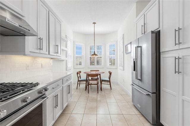 kitchen featuring hanging light fixtures, backsplash, stainless steel appliances, white cabinets, and light tile patterned flooring