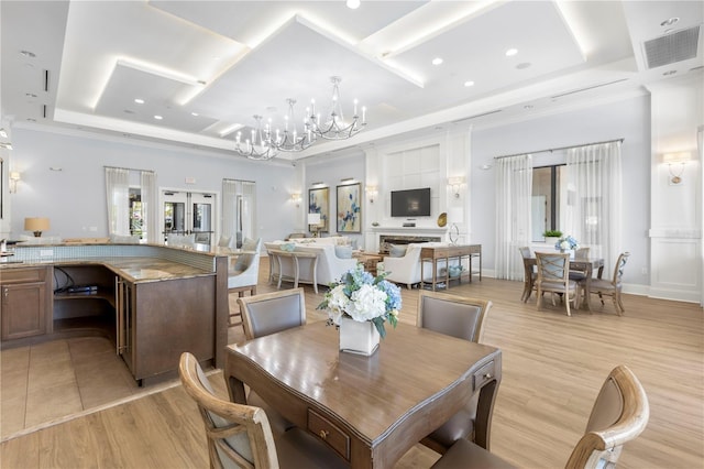 dining area with a notable chandelier, a tray ceiling, ornamental molding, and light hardwood / wood-style floors