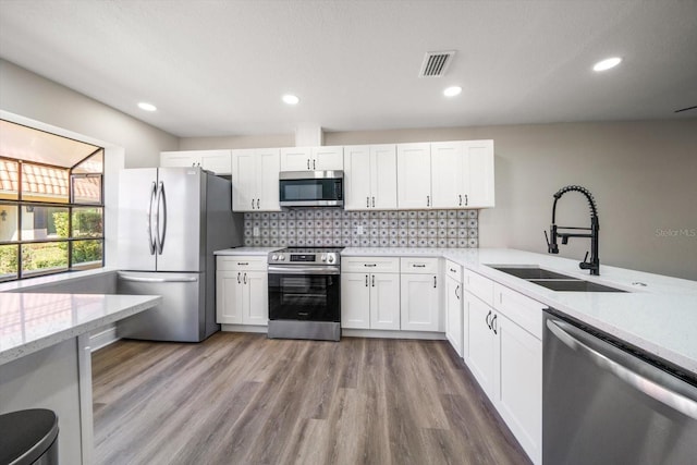 kitchen featuring sink, tasteful backsplash, stainless steel appliances, hardwood / wood-style floors, and white cabinets