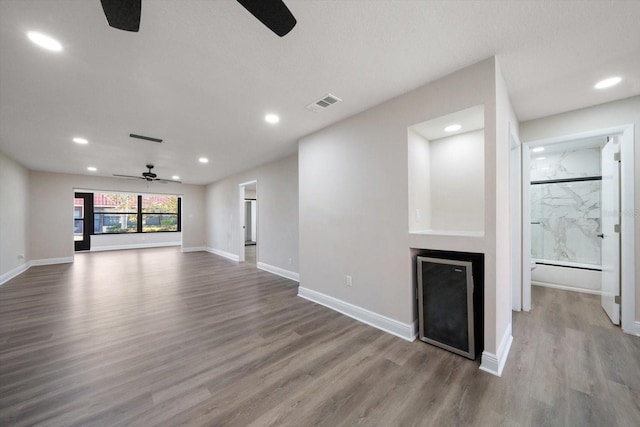 unfurnished living room featuring wood-type flooring, ceiling fan, and baseboard heating