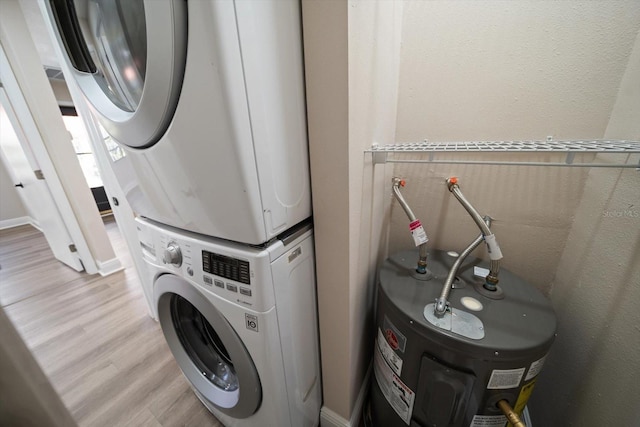 washroom featuring stacked washer / dryer, light wood-type flooring, and water heater