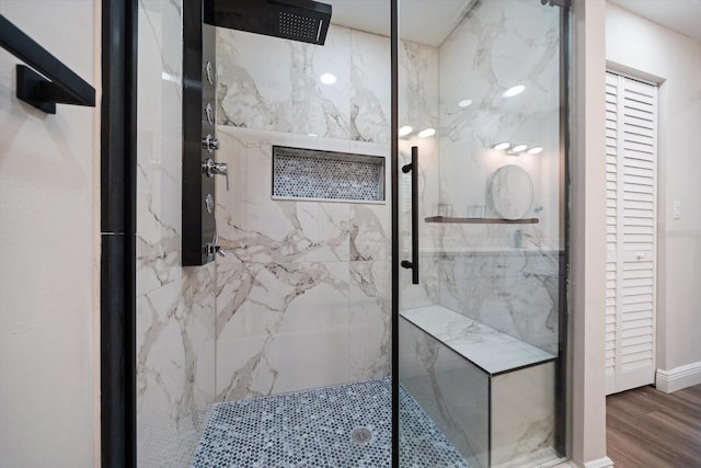 bathroom with a tile shower and hardwood / wood-style flooring