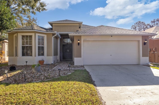 view of front of home with driveway, roof with shingles, a garage, and stucco siding