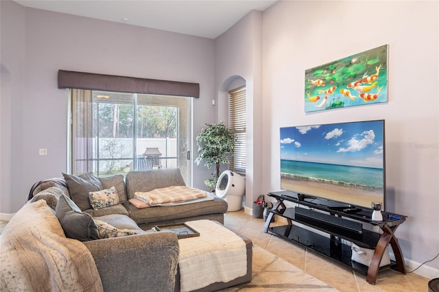 living room featuring arched walkways, baseboards, and tile patterned floors