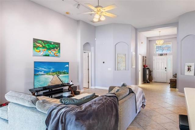 living room with arched walkways, light tile patterned flooring, a towering ceiling, and baseboards