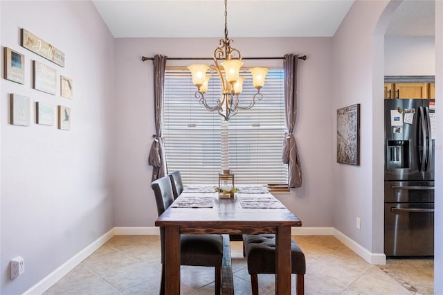 dining area featuring light tile patterned floors, baseboards, arched walkways, and a chandelier