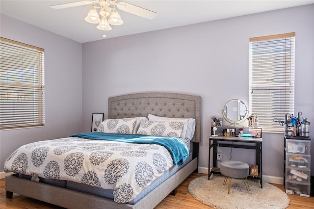 bedroom featuring multiple windows, baseboards, and wood finished floors