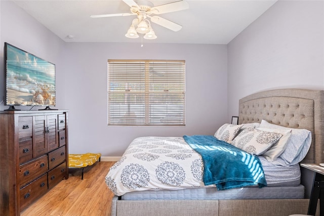 bedroom featuring light wood finished floors, a ceiling fan, and baseboards