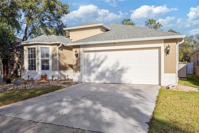 view of front facade featuring concrete driveway, roof with shingles, an attached garage, and stucco siding