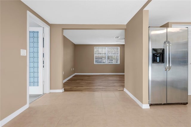 interior space featuring stainless steel refrigerator with ice dispenser and light tile patterned floors