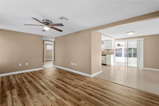 empty room with a textured ceiling, light hardwood / wood-style flooring, and ceiling fan