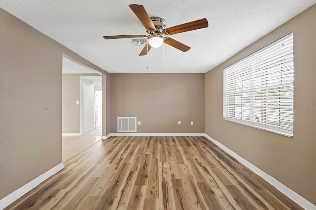 empty room featuring ceiling fan, light hardwood / wood-style floors, and a textured ceiling