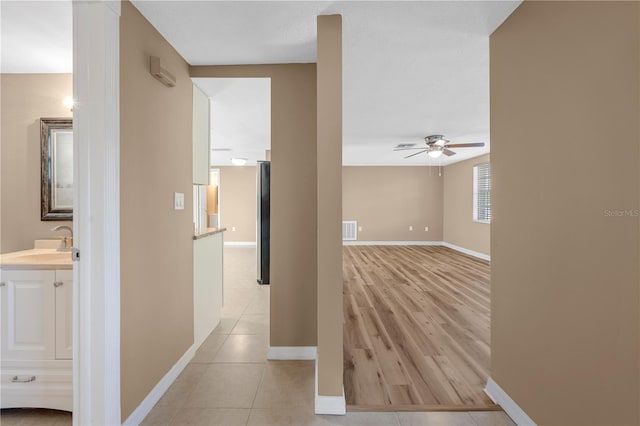 corridor featuring sink and light tile patterned floors