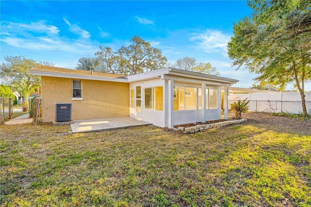 rear view of property featuring central AC unit, a yard, and a sunroom