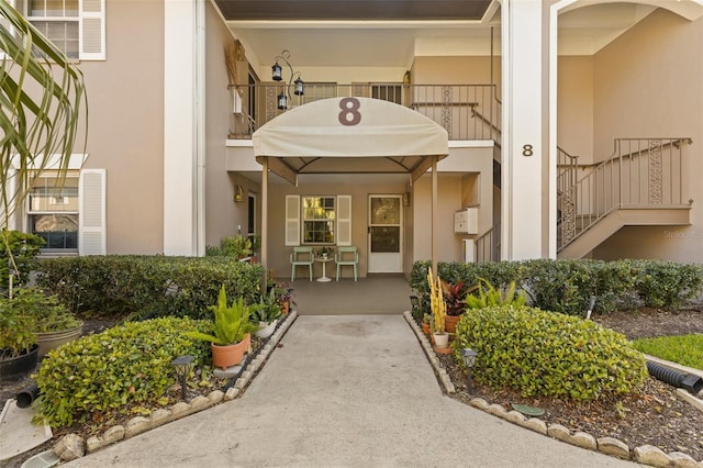 view of exterior entry featuring a balcony and stucco siding