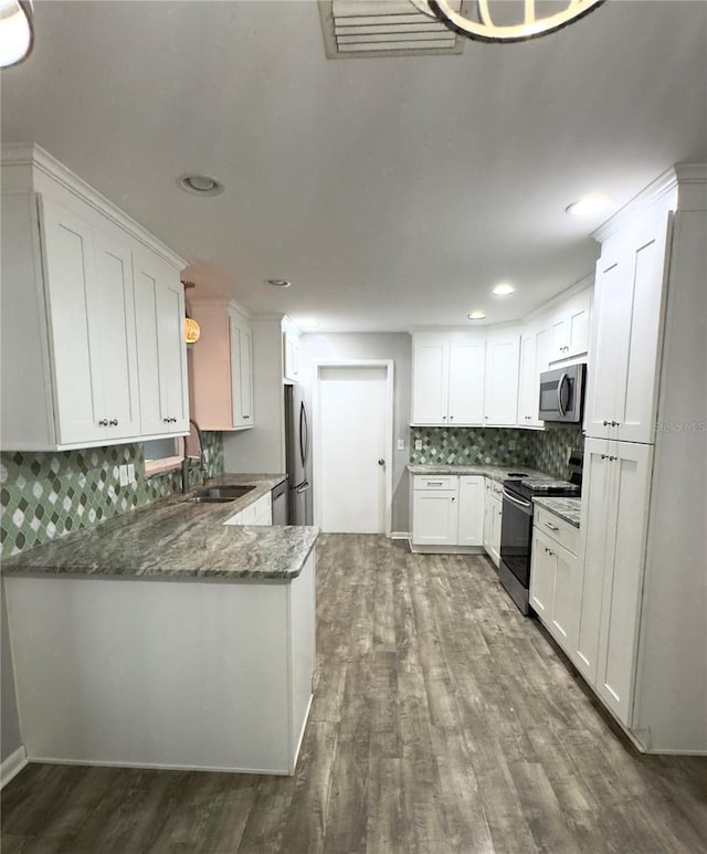 kitchen with dark stone countertops, stainless steel appliances, sink, and white cabinets