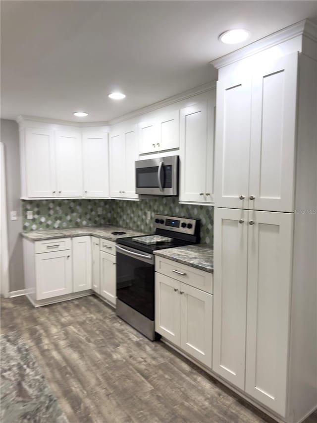 kitchen with tasteful backsplash, white cabinetry, appliances with stainless steel finishes, and dark wood-type flooring