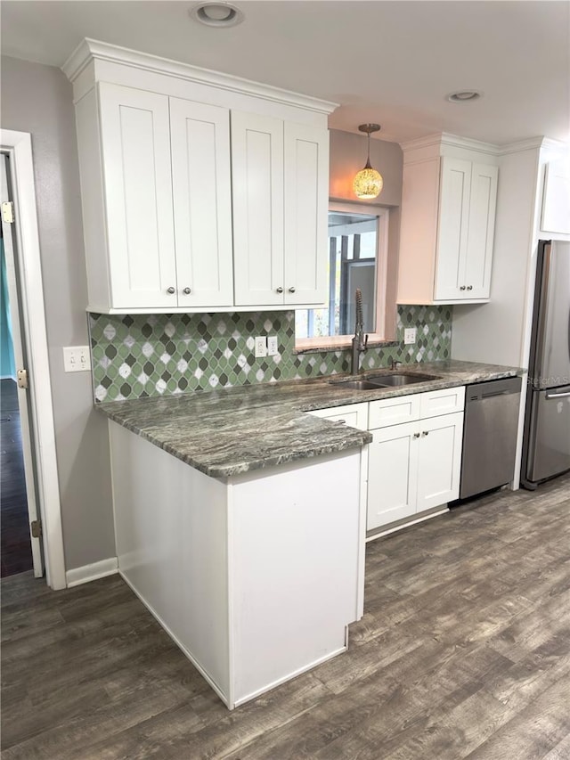 kitchen with appliances with stainless steel finishes, pendant lighting, sink, white cabinets, and dark hardwood / wood-style flooring