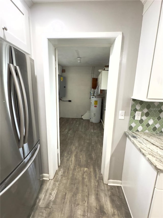 kitchen featuring stainless steel fridge, water heater, light stone counters, white cabinets, and decorative backsplash