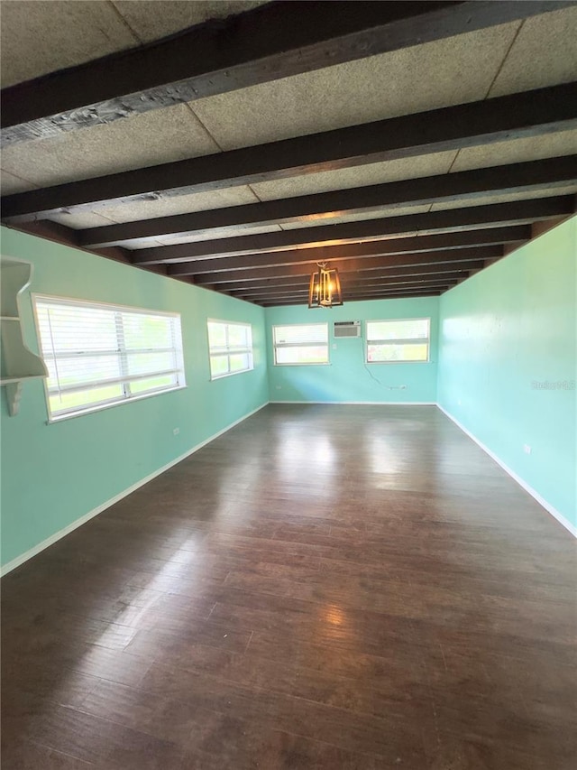 spare room featuring dark hardwood / wood-style flooring, plenty of natural light, and beamed ceiling