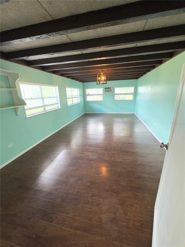 spare room with beamed ceiling, a wealth of natural light, and dark hardwood / wood-style flooring