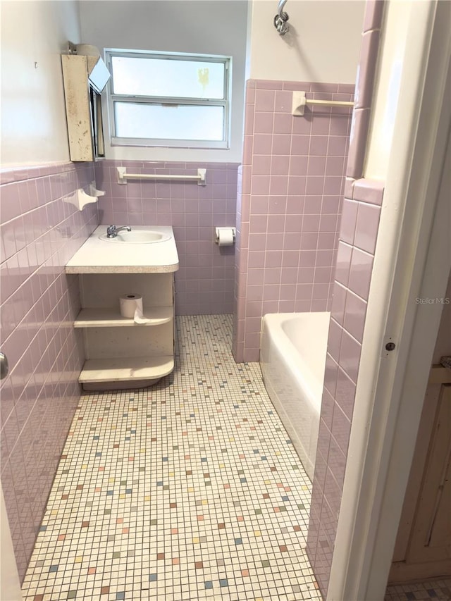 bathroom with tile walls, vanity, a washtub, and tile patterned floors