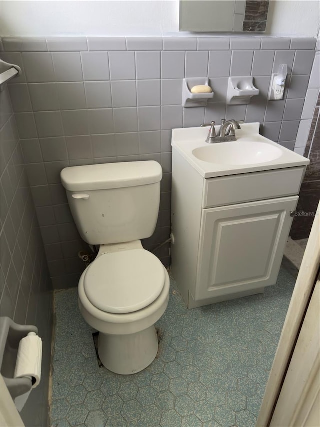 bathroom with vanity, toilet, and tile walls