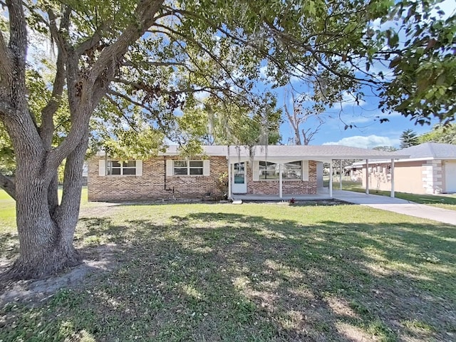 single story home with a front yard, concrete driveway, a carport, and brick siding