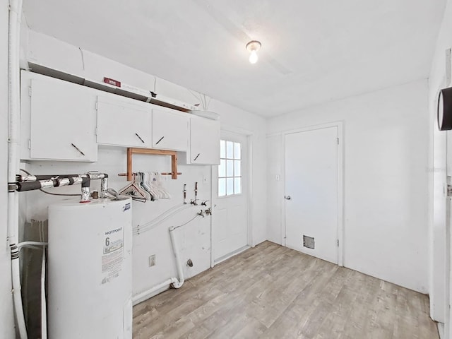 laundry area with water heater and light wood finished floors