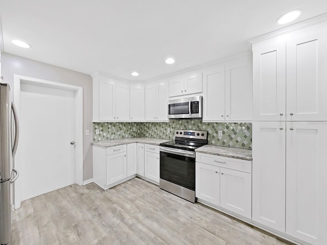 kitchen featuring light stone countertops, light wood-style flooring, stainless steel appliances, decorative backsplash, and white cabinets