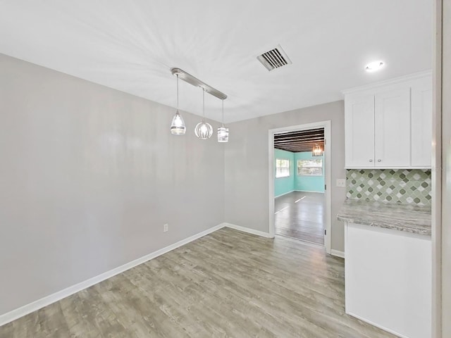 unfurnished dining area with visible vents, baseboards, and light wood-style floors