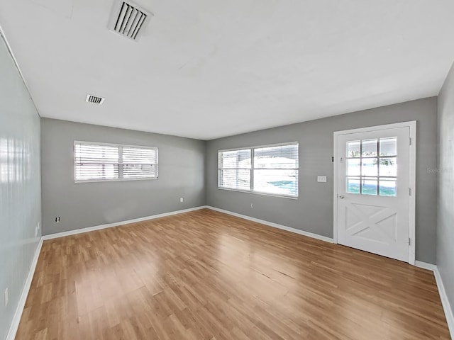 unfurnished living room with light wood finished floors, visible vents, and baseboards