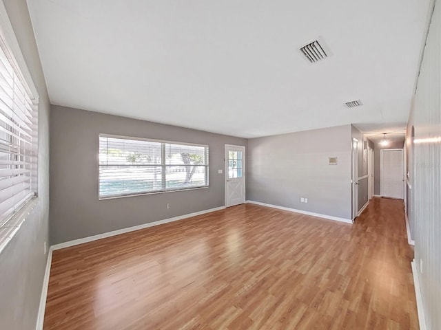 unfurnished living room featuring light wood finished floors, visible vents, and baseboards