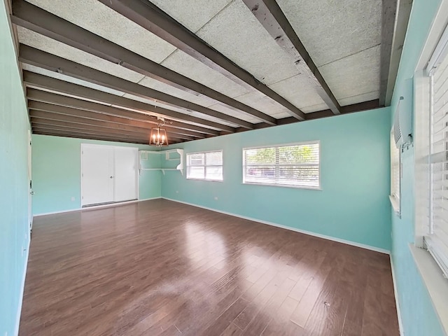 unfurnished room with dark wood-type flooring, baseboards, and beam ceiling