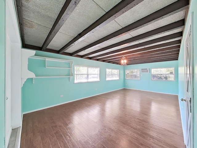 spare room with beamed ceiling, wood finished floors, and baseboards