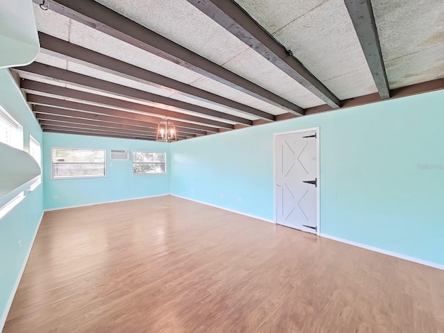 basement with an inviting chandelier, wood finished floors, and baseboards