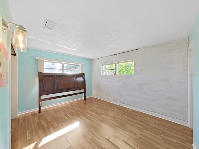 unfurnished bedroom with wood finished floors, visible vents, and baseboards