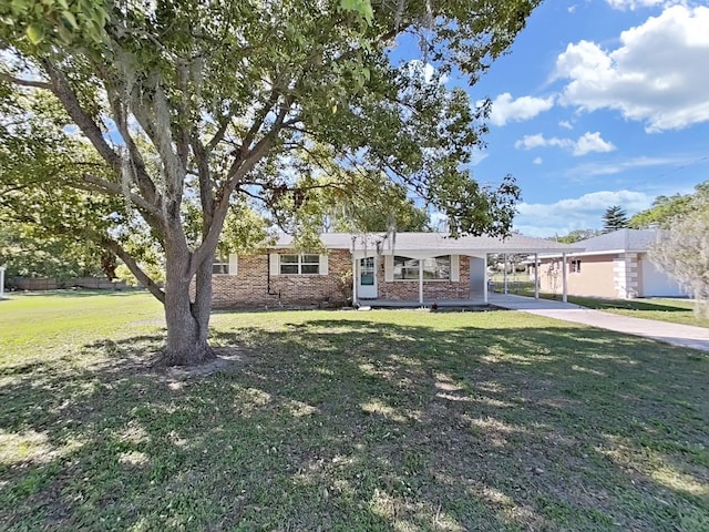 ranch-style home with brick siding, an attached carport, driveway, and a front lawn