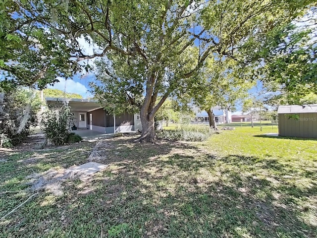 view of yard featuring a shed, an outdoor structure, and a sunroom