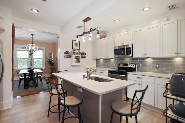 kitchen featuring a sink, stainless steel appliances, hanging light fixtures, and light countertops