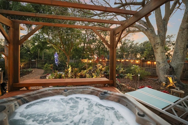 patio terrace at dusk featuring an outdoor hot tub