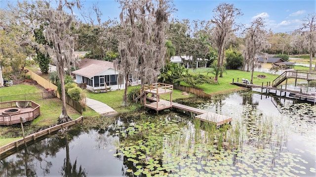 dock area featuring a water view, a lawn, and a fenced backyard