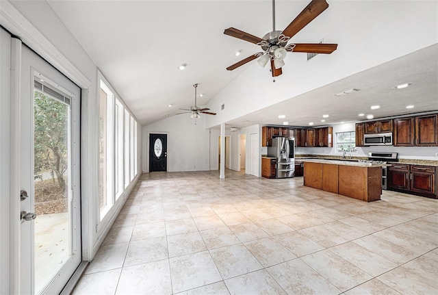 kitchen with light tile patterned floors, a kitchen island, open floor plan, stainless steel appliances, and light countertops