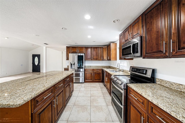 kitchen with light tile patterned flooring, a kitchen island, a sink, appliances with stainless steel finishes, and light stone countertops