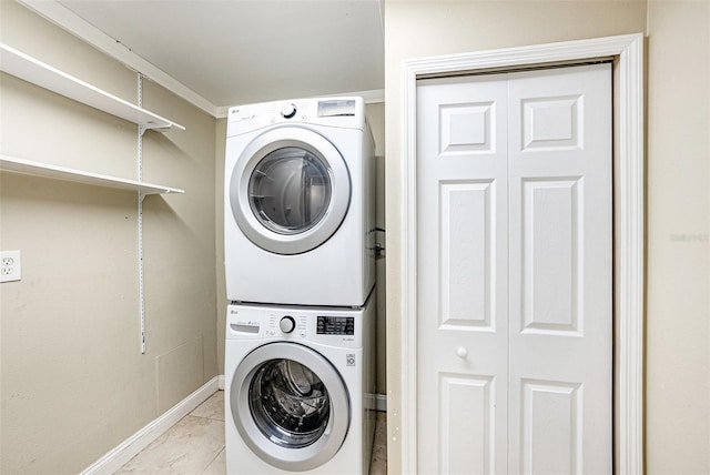 washroom with laundry area, baseboards, and stacked washer and clothes dryer