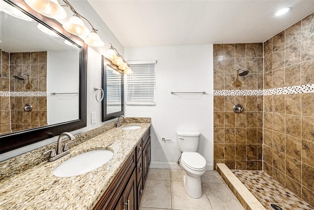 bathroom featuring a tile shower, a sink, and toilet