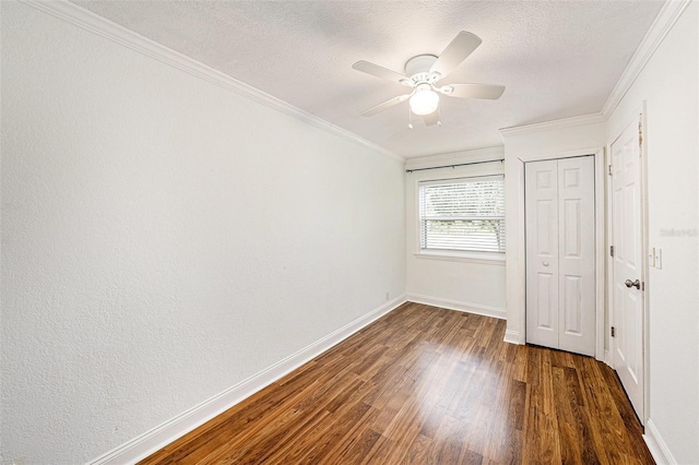 unfurnished bedroom featuring a textured ceiling, baseboards, ornamental molding, a closet, and dark wood finished floors